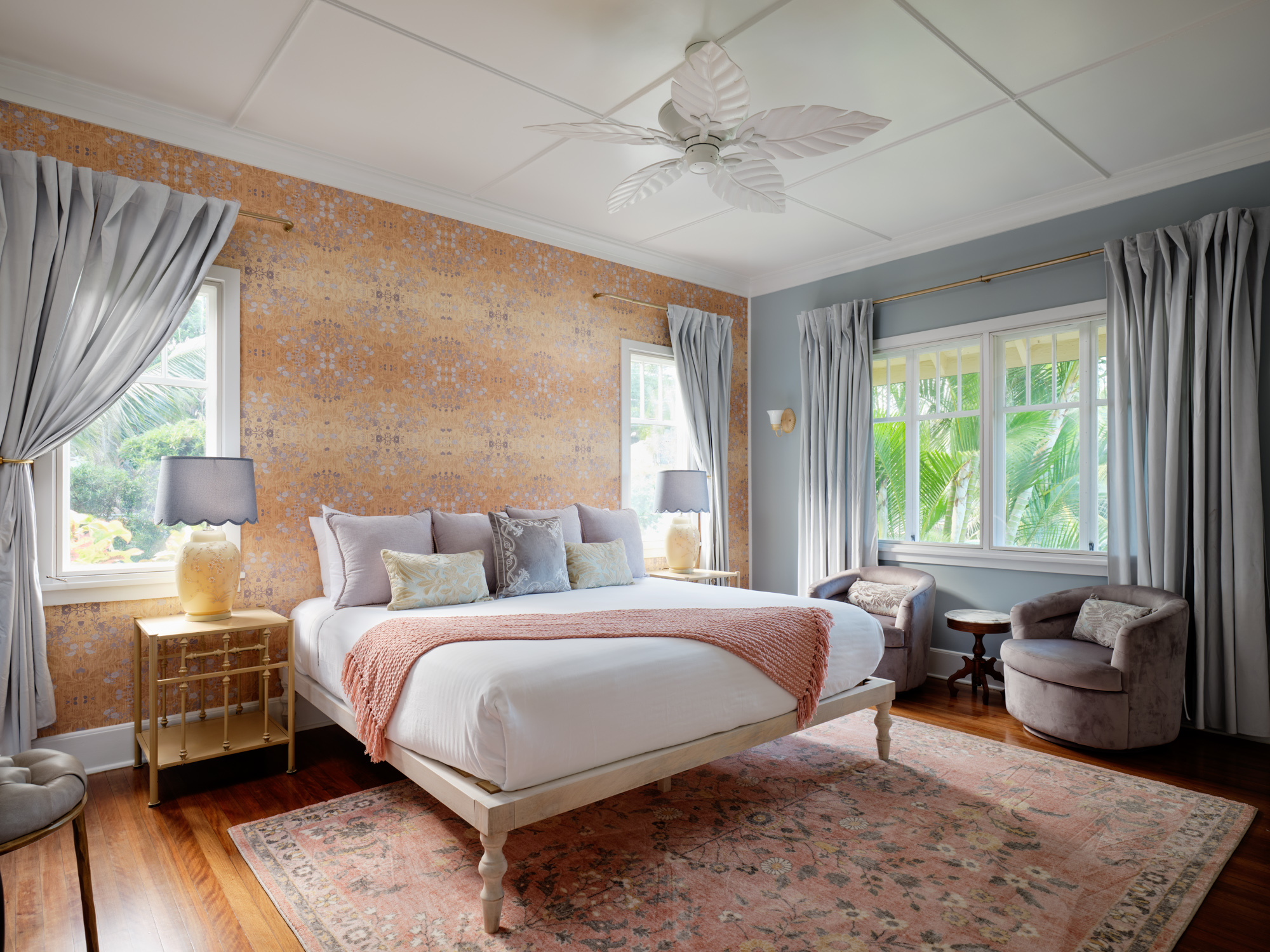 A flower-named guest suite — warm wallpaper, a made bed, antique furnishings